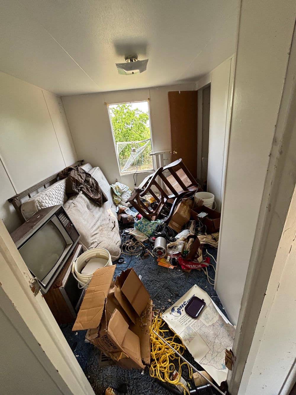 Cluttered room filled with trash, old furniture, and disorganized items, showcasing neglect.
